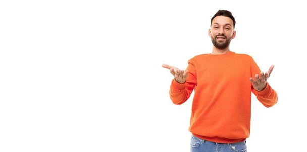 мужчина в оранжевом свитере протягивает руки вперед, с волнением глядя в камеру - Фото, изображение