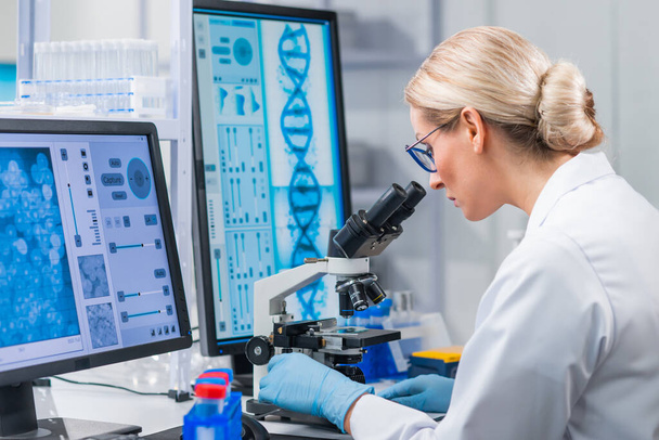 Professional female scientist is working on a vaccine in a modern scientific research laboratory. Genetic engineer workplace. Future technology and science. - 写真・画像