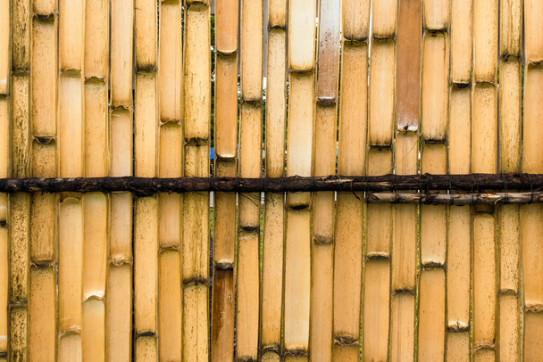 Pared simple de bambú de tono marrón antiguo o fondo de textura de valla de bambú para el diseño interior o exterior tono vintage. Fondo de patrón de palo de bambú marrón. Área local protección de la casa urbana contra ladrón. - Foto, imagen