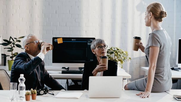 Business people holding coffee to go near devices and headset in office  - Photo, Image