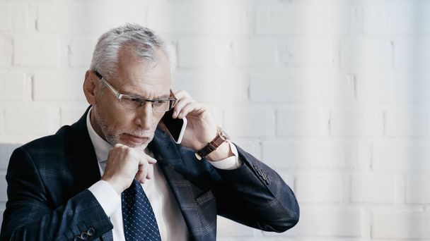 Pensive businessman talking on mobile phone in office  - Fotografie, Obrázek
