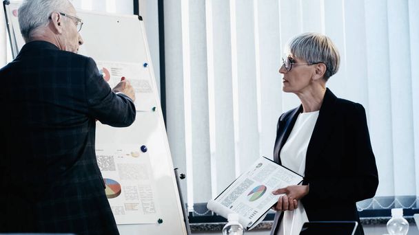 Mature business people working with papers on flip chart in office  - Valokuva, kuva