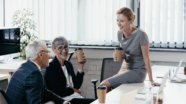 Felici uomini d'affari che tengono bicchieri di carta mentre parlano in ufficio  - Foto, immagini