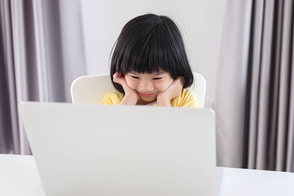 klein aziatisch meisje student studeren online met behulp van laptop computer thuis - Foto, afbeelding