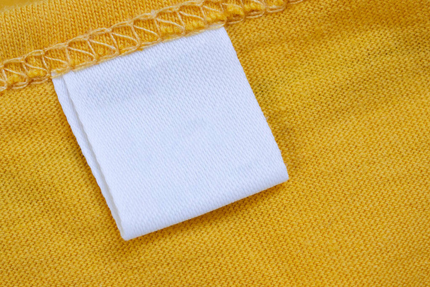 Bílé prázdné oblečení štítek na nové žluté košili pozadí - Fotografie, Obrázek