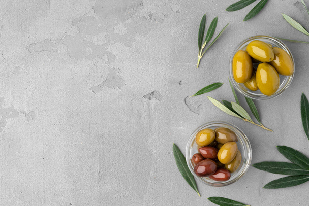Glass bowl with marinated olives on gray background top view - Fotografie, Obrázek
