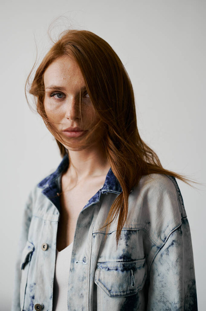 Nice model with red hair, blue eyes and long wavy red hair. Sensual attractive woman. Freckles. Neutral background. Excellent quality. Soft light. Jean jacket. Nice lashes, big lips, beautiful eyes - Fotó, kép