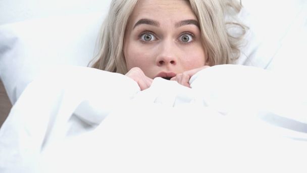 young shocked woman covering with white blanket in bed - Foto, Imagen