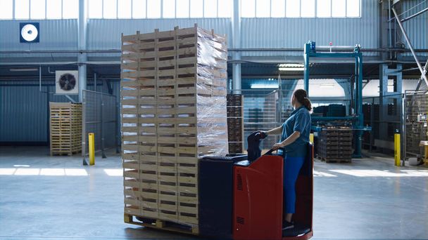 Mulher armazém trabalhador transportando paletes de condução máquina de armazenamento caixas móveis - Foto, Imagem