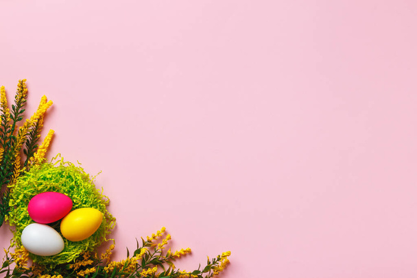 Top view of easter eggs and flower twigs on pink background. Flat lay with copy space - Foto, afbeelding