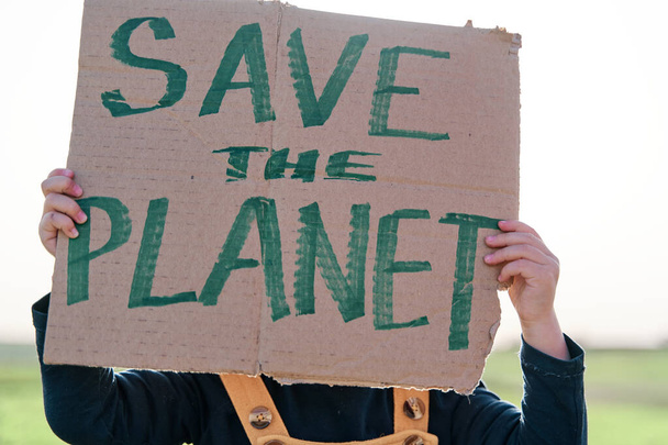 Girl's hand holding a cardboard sign that says SAVE THE PLANET - Photo, Image