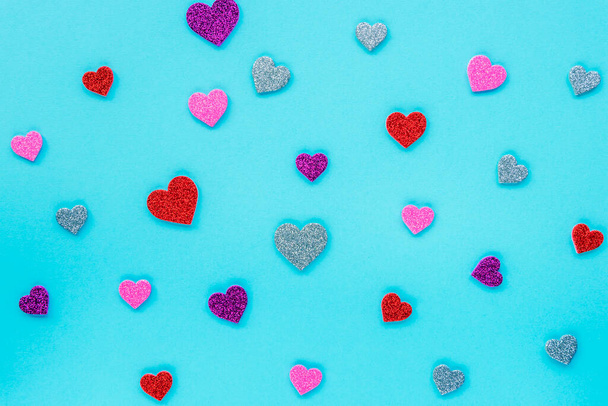 Roze, rode, paarse en zilveren glinsterende harten op een blauwe achtergrond. Valentijnsdag concept. Textuur, achtergrond. - Foto, afbeelding
