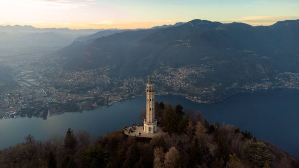 Aerial drone view of a lighthouse over Lake Como skyline with sunset light - Faro Voltiano (Volta Lighthouse) - Travel Destination, Brunate, Como, Lombardy, Italy - Photo, Image