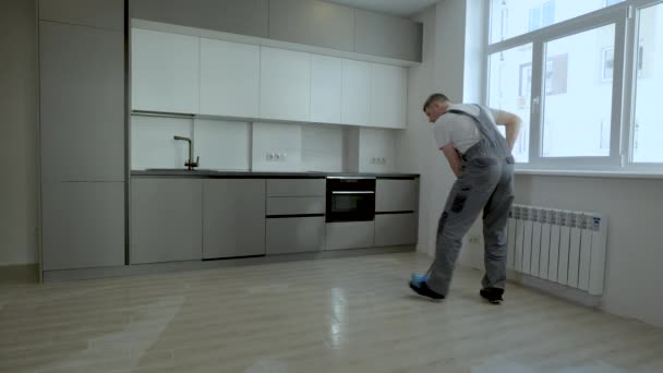 A builder in uniform washes the floor in a new apartment - Záběry, video