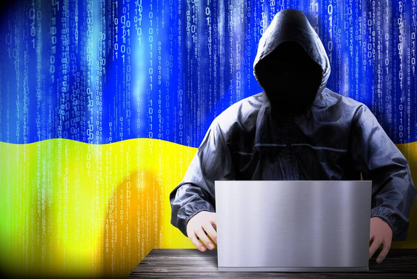 Pirate anonyme à capuchon, drapeau de l'Ukraine, code binaire - concept de cyberattaque - Photo, image