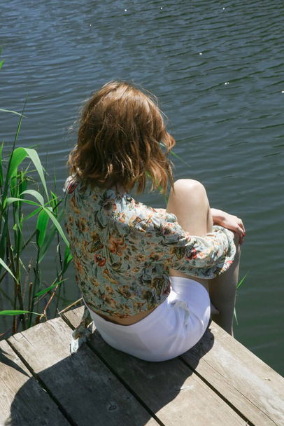 Woman in floral blouse and white shorts enjoying sunny day in nature - Photo, Image