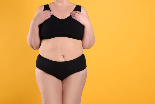 Overweight woman in underwear on orange background, closeup. Space for text - Fotografie, Obrázek