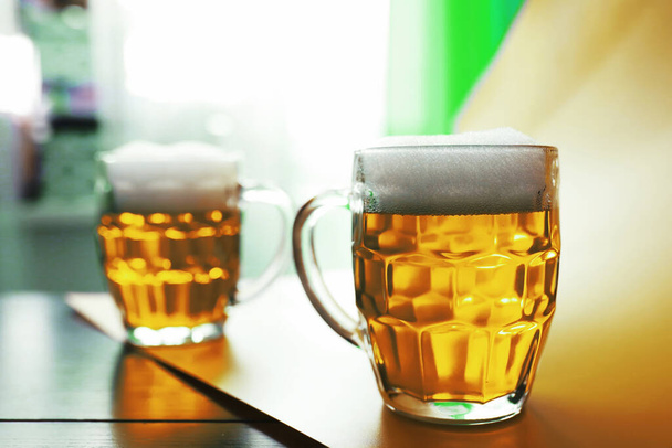 聖パトリックの祝日。アイルランドの祝日。緑のビール。バーでマグカップエメラルドビールと手. - 写真・画像