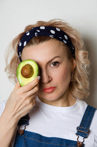A woman holds a cut avocado in her hands, with her hair down, with healthy skin, leads a healthy, correct lifestyle.Healthy food, keto diet, vegetarianism. - 写真・画像