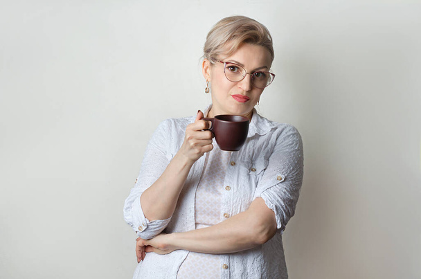 Γυναίκα με ένα φλιτζάνι καφέ, τσάι στα χέρια της. - Φωτογραφία, εικόνα