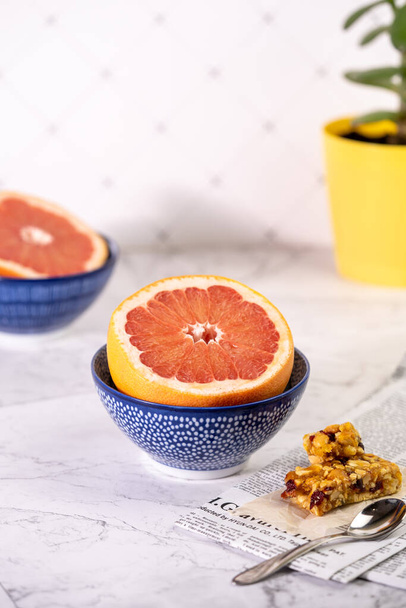 Gesundes Frühstück mit Grapefruit und Müsliriegel mit Nüssen. Kopierraum. Vertikales Bild - Foto, Bild