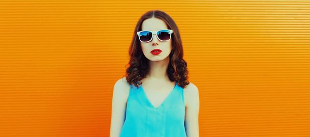 Portrait of young woman posing wearing dress on an orange background - Photo, Image