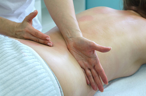 Γυναίκα επαγγελματίας μασέρ δείχνει τεχνικές μασάζ. Μασάζ πλάτης με σκοπό την επούλωση, τη μυϊκή χαλάρωση και θεραπεία. - Φωτογραφία, εικόνα