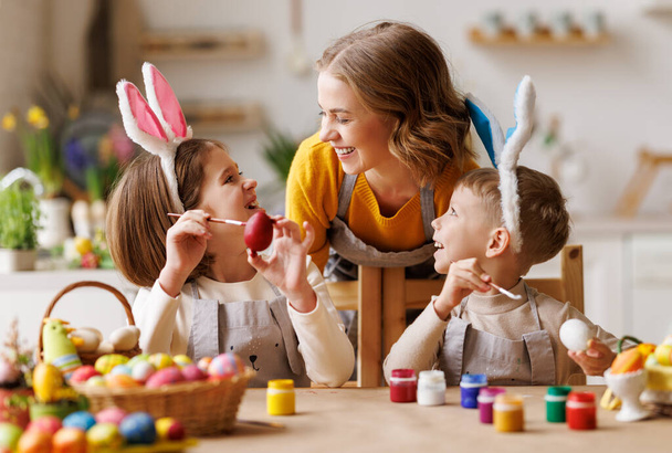 Счастливой Пасхи. мать семьи и веселые дети с ушами готовятся к празднику - Фото, изображение