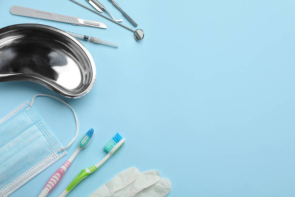 Set of different dentist's tools, face mask, toothbrushes and glove on light blue background, flat lay. Space for text - Φωτογραφία, εικόνα