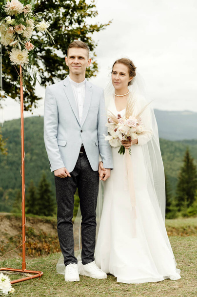 bride and groom near the arch during the wedding ceremony. wedding couple in the mountains near a branchy tree - Foto, Bild