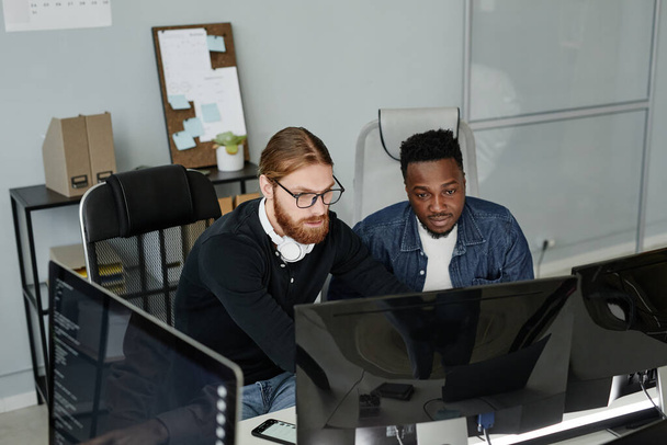 眼鏡の若い髭の男と彼の同僚は、コンピュータの画面を見て - 写真・画像