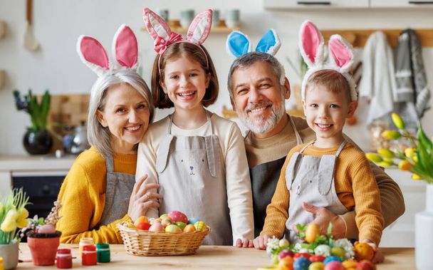 Family Easter traditions. Happy grandparents and kids in bunny ears headbands paint eggs together - Photo, Image