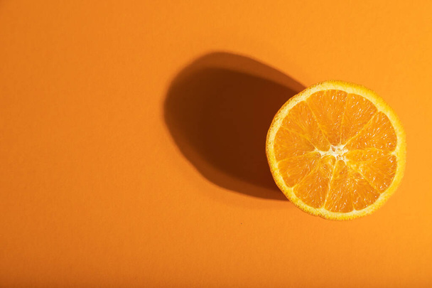 Ripe cut orange on orange pastel background. Top view, flat lay, copy space, hard light. Tropical, healthy food, concept, minimalism. - Foto, imagen