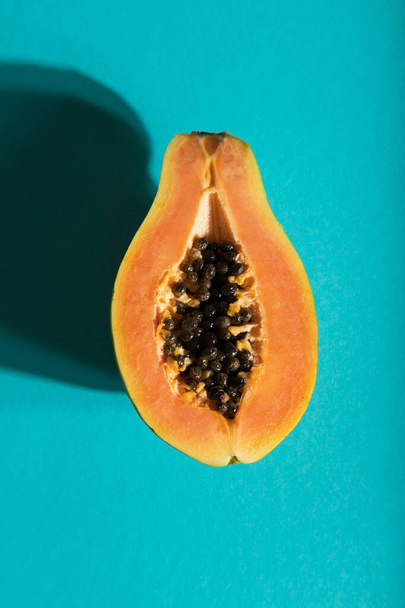 Rijp gesneden papaya op blauwe pastelachtergrond. Bovenaanzicht, vlak, close-up, hard licht. Tropisch, gezond voedsel, gezondheidsconcept voor vrouwen, minimalisme. - Foto, afbeelding