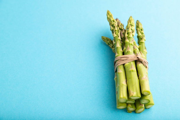 Un mazzo di asparagi verdi freschi su sfondo blu pastello. Vista laterale, copiare spazio. raccolto, cibo sano, vegano, concetto, minimalismo. - Foto, immagini