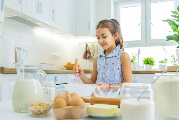 L'enfant dans la cuisine prépare la pâte dans la cuisine. Concentration sélective. Produits alimentaires. - Photo, image