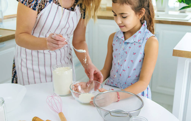Gyermek és anya a konyhában süti készíti a tésztát a konyhában. Szelektív fókusz. Emberek.. - Fotó, kép