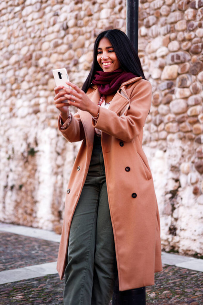 beautiful happy indian woman using cellphone outdoors, vertical portrait - Photo, Image