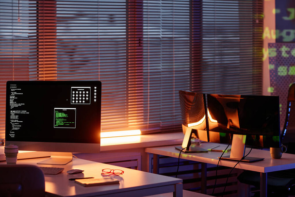 Fila de escritorios con monitores de ordenador de pie junto a la ventana con persianas venecianas - Foto, Imagen