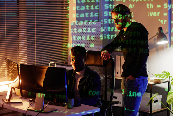 Zwei junge interkulturelle Programmentwickler blicken auf den Computerbildschirm - Foto, Bild