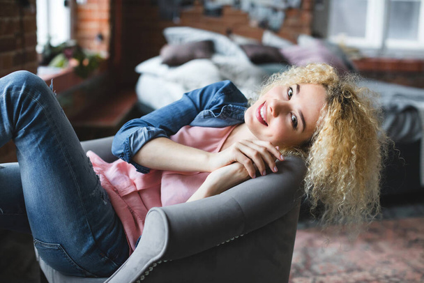 Happy smiling curly blonde woman in denim at home. - Fotoğraf, Görsel