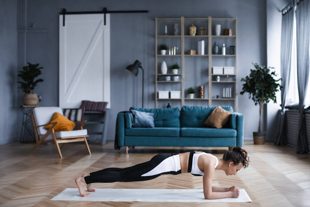 Sportive brunette fitness woman doing exercises in living room. Alone at home. - Foto, Imagem