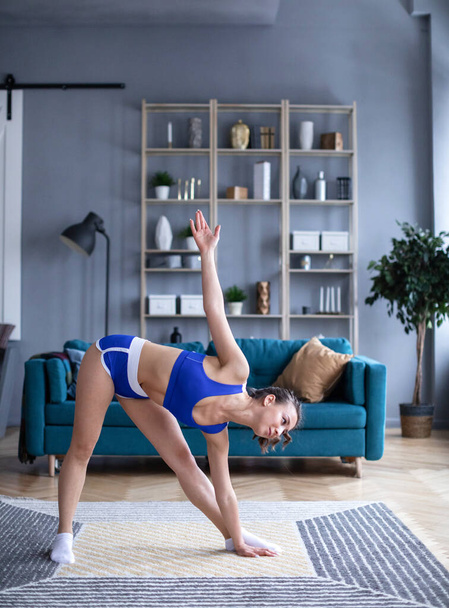 Brunette fitness woman make stretching exercises in living room. Alone at home. - Valokuva, kuva
