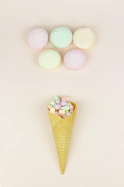 Waffle horn with colored marshmallow looks like macaroons on a pink pastel background - Foto, imagen