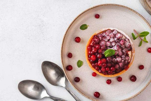 Crostata di bacche fresche con cowberry, zucchero a velo e menta in un piatto su sfondo bianco. Dolce saporito. Vista dall'alto con spazio di copia - Foto, immagini