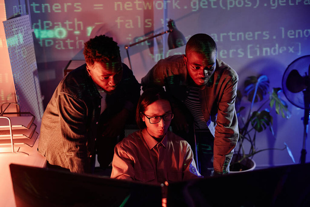 Skupina mladých interkulturních programátorů ohýbající se před počítačovými monitory - Fotografie, Obrázek