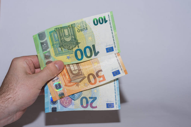 Drei-Euro-Scheine in einer Hand seitlich mit grauem Hintergrund - Foto, Bild