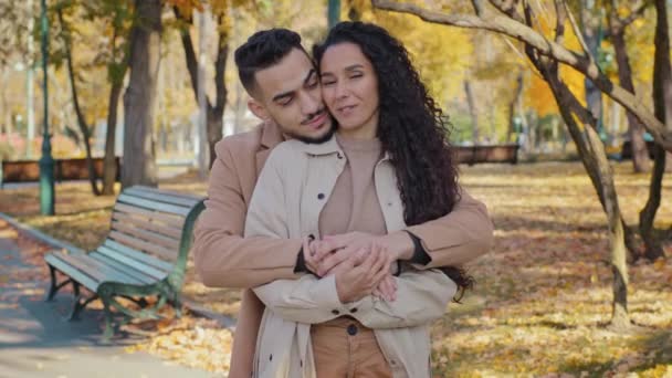 Spaanse man knuffels vriendin van rug paar verliefd veel plezier communiceren kijken in afstand bespreken gezamenlijke toekomst in de herfst park jong gezin omarmen gevoel gelukkig buitenshuis romantisch date concept - Video