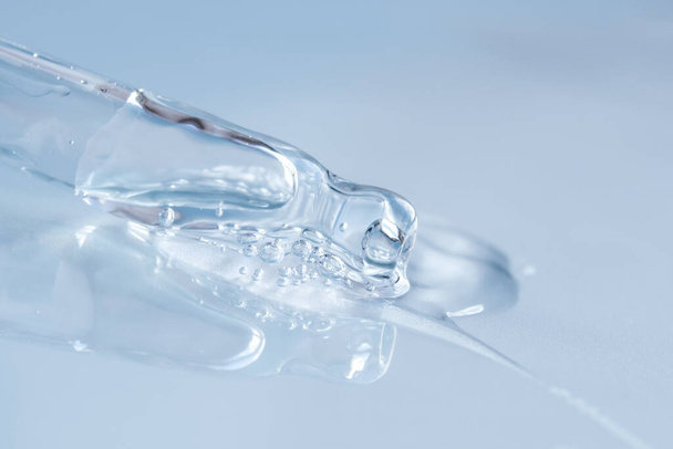 Pipette with fluid hyaluronic acid on monochrome blue background. Cosmetics and healthcare concept closeup - 写真・画像