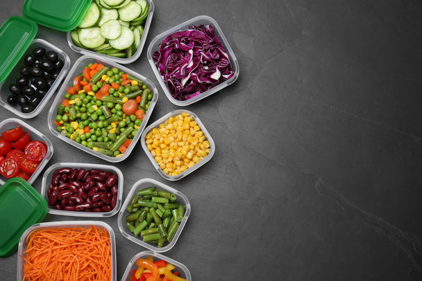 Set of plastic containers with fresh food on black table, flat lay. Space for text - Photo, Image